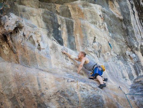 Young man rock climbing on karst limestone white mountain in Thailand