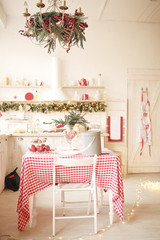 Christmas decoration. New Year's home interior. Garlands in bokeh. Beautiful red and white plates and cups on  the kitchen. Cozy atmosphere.