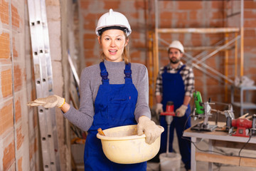 Portrait of two builders in process of finishing work in cottage