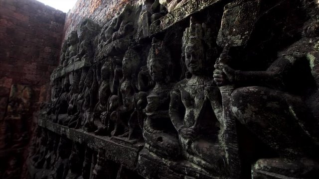 Closeup view of amazingly detailed stone carvings on the wall of the Terrrace of the Leper King under sunbeams. It is located in the northwest corner of the Royal Square of Angkor Thom, Cambodia.