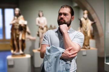 Man looking at stone architectural elements in historical museum hall