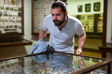 Attentive adult man exploring artworks in glass case in museum