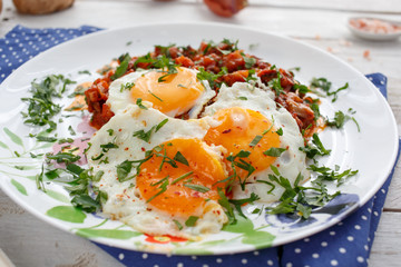 Breakfast with fried eggs and vegetables with tomato sauce