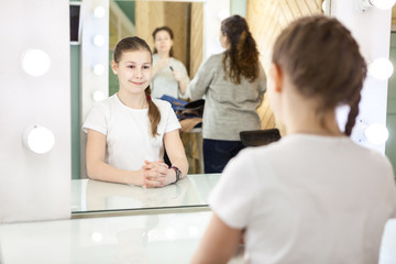 Naklejka na ściany i meble Mother and teenager girl preparing for photoshooting in dressing room in front of mirror