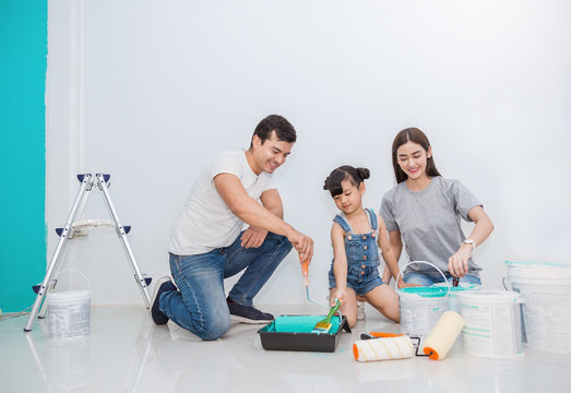 Portrait Of Happy Smiling Asian Family Renovating Painting Wall House. Mother Father And Child Daughter Repairing Paint Wall At Home. Together Love Lifestyle Concept With Copy Space.