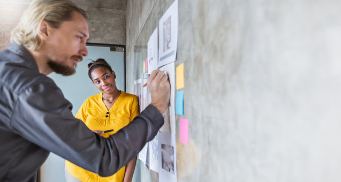 Portrait of business people meeting at office and use sticky notes to share ideas. Brainstorming together teamwork synergy acquisition concept.  Coworker writing in note pad on the wall.