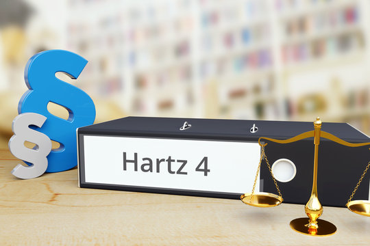 Hartz 4 (ALG II) – Recht/Gesetz. Ordner auf Schreibtisch mit Beschriftung neben Paragraf und Waage. Anwalt