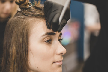 Eyebrow dyeing. The master paints eyebrows with henna to a beautiful girl, paints with a brush in...