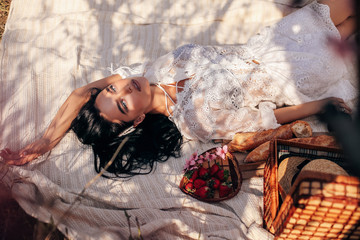 beautiful sensual woman with dark hair in elegant dress posing among flowering peach trees