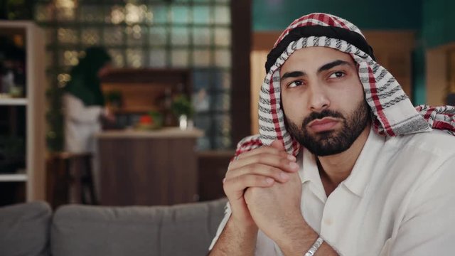 Portrait serious young man wearing traditional emirates clothes thinking male saudi arab arabic business muslim traditional sheik posing headscarf sheikh face close up slow motion
