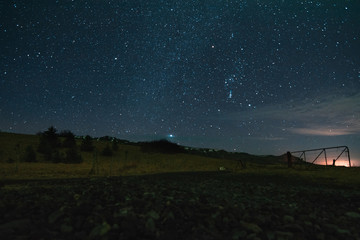 Mountains and path leading to field in the evening, the stars all over the sky