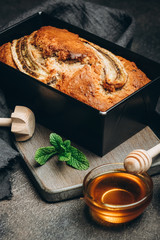 Banana bread with nuts, honey and mint on a dark background.