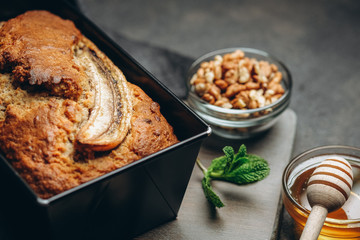 Banana bread with nuts, honey and mint on a dark background.