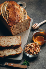 Banana bread with nuts, honey and mint on a dark background.