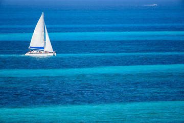 Velero de dos velas navegando en el mar caribe con contraste colores azul turquesa, Cancun, Mexico  © lduarte