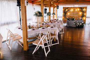 Stylish wooden restaurant decorated by greenery with black loft lamps. Wedding reception. Banquet. Decor