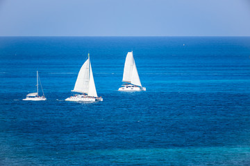 Grupo de Veleros de dos velas en competencia regata en el mar caribe con contraste colores azul turquesa, Cancun, Mexico 