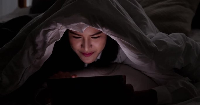 Woman using tablet on bed at night or dark room. People with technology concept.