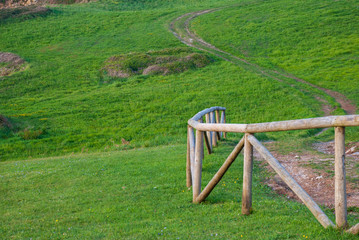 Close-up of curved wooden fence in a green field