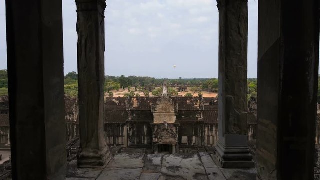 Time lapse zooming out vew from central tower of Angkor Wat complex, jungle behind it and yellow turistic balloon in the air. Cambodia