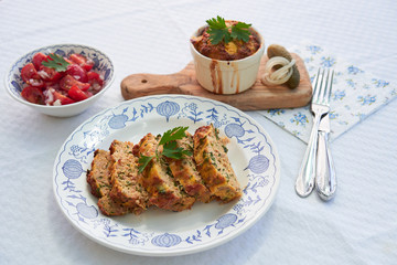 Close up Picture on the traditional baked czech spring dish, kind of salt cake or quiche, made from eggs, smoked ham, bread, pork meat and parsley, served on rustic plate with fresh tomato salad.
