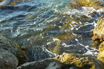 The wreckage of rocks in the sea near the rocky shore in the sea foam.