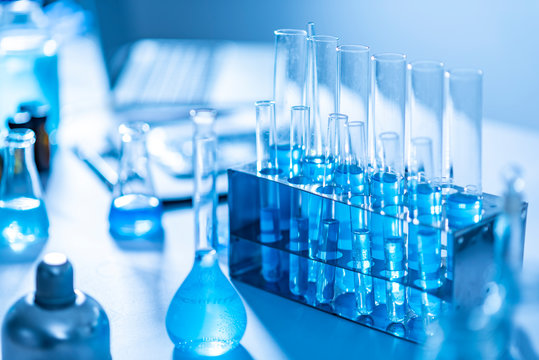 Different laboratory glassware with color liquid and with reflection, blue tone