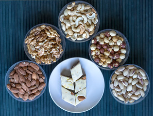Fototapeta na wymiar Oriental dessert halva with pistachio, almond, cashew nuts, peanut, walnut on a plate. Image. Healthy food. Nuts mix assortment. sweets, Turkish Delight. Isolated background.. Eastern delicacy