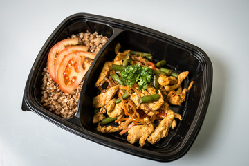 food in lunch boxes, side dish buckwheat, baked chicken, healthy food, black box on white background