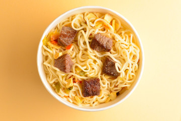Paper cup with instant ramen noodles with beef and vegetables.