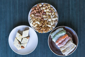 Oriental dessert halva with pistachio, almond, cashew nuts, peanut, walnut  on a  plate. Image. Healthy food. closeup of sweets from Iran popular  Turkish Delight. Isolated on background