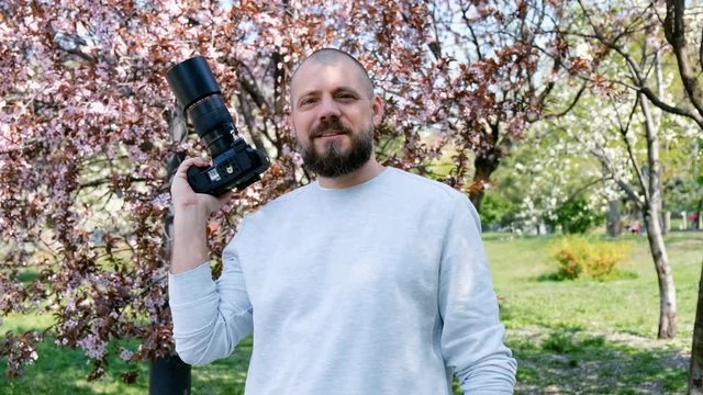 Portrait of handsome photographer with blooming sakuras on a background