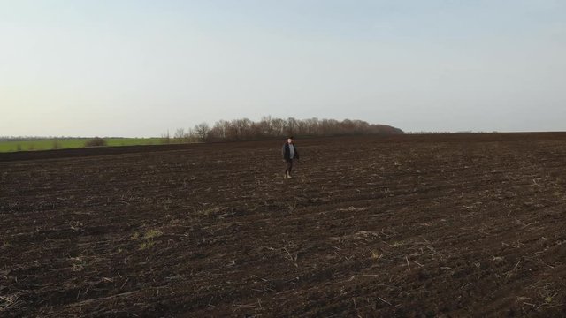 Adult farmer examining plowed field, preparing land for sowing. Seasonal agricultural works concept.
