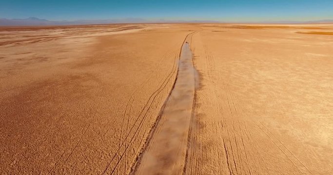 SALAR DE TARA, ATACAMA DESERT, CHILE - JUNE 2016. Aerial view of the red car during the bumpy drive out to the salt flats. Rust-colored country road along windswept Atacama Desert.