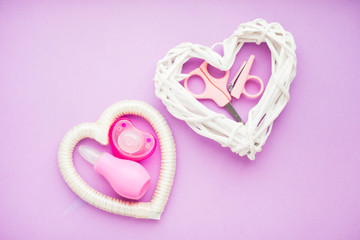 Newborn baby story. Strow heart and children's toys, scissors, baby bottle, nipple, hairbrush on violet background