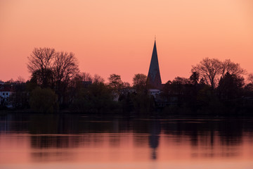 Silhouette von Eutin mit Kirchturm über dem kleinen See im Morgenrot , Schleswig-Holstein