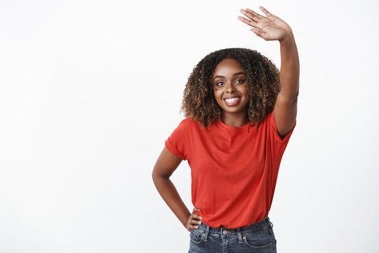 Bye see you later, take care. Portrait of friendly and sincere kind gentle african-american woman waving raised palm in greeting or goodbye gesture smiling holding hand on waist over white background