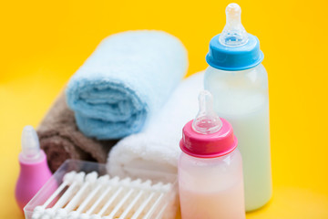 Newborn baby story. Towels and children's toys, scissors, baby bottle, nipple, hairbrush on yellow background