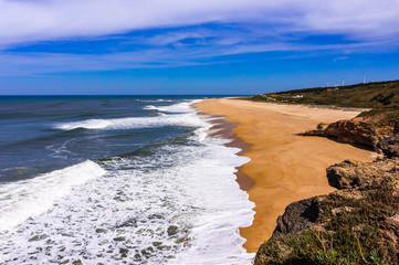 Empty long Nazare sandy beach with cliff Atlantic Ocean