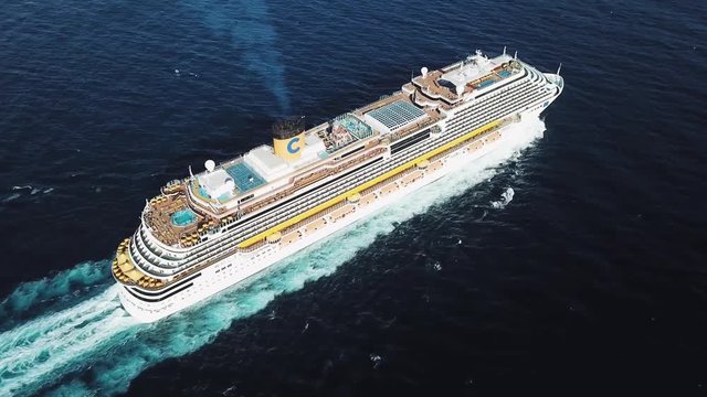 Aerial top view of stunning cruise ship at Black sea. Stock. Large cruise ship with people on the upper deck and a swimming pool with basketball field.