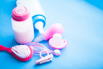 Newborn baby story. Children's toys, scissors, baby bottle, nipple, hairbrush on blue background