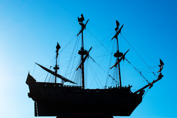 Silhouette of a frigate on a blue clear sky. Three-masted sailing ship soaring in the air.