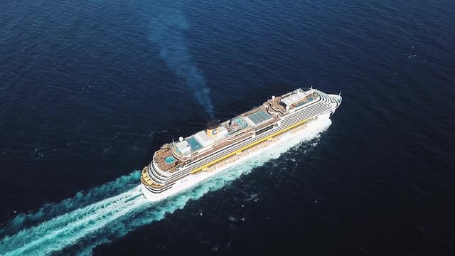 Top view of a beautiful white cruise ship in the Atlantic ocean, luxury vacation. Stock. Aerial for the passenger liner with many people on board relaxing under the bright sun.