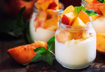 Dessert with sweet peaches, cottage cheese and whipped cream, served in glass jars, vintage wooden...