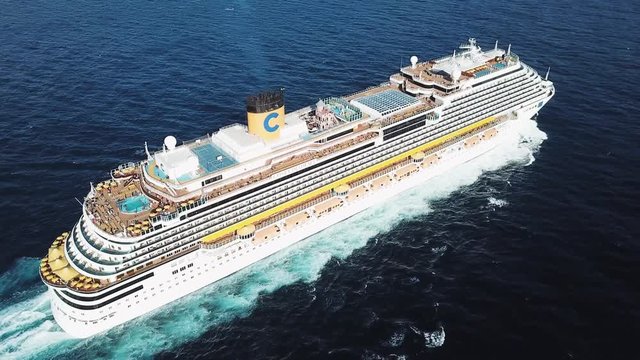 Top view of a beautiful white cruise ship in the Atlantic ocean, luxury vacation. Stock. Aerial for the passenger liner with many people on board relaxing under the bright sun.
