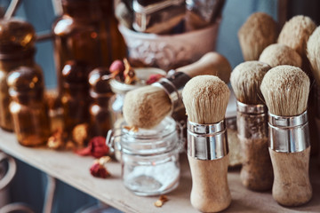 Glass jars, different brushes and other tools on a shelf at art studio.