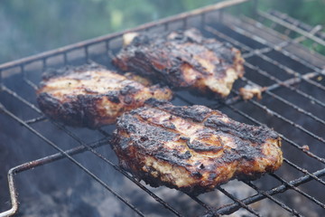 Large pieces of meat steaks are cooked on the grill