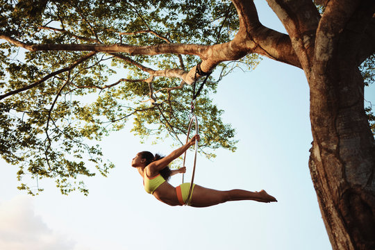 Young African American Woman Training With Aerial Hoop Hanging on Tree