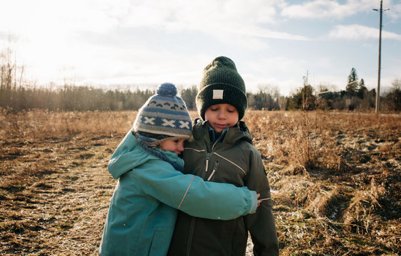 brother and sister hugging boy and girl cuddling outdoors playing