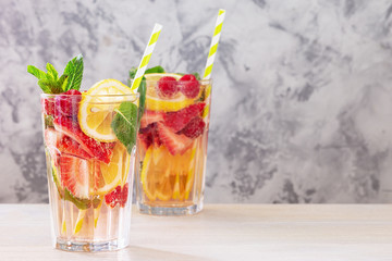 Two glasses with lemonade from lemon, strawberry, raspberry and mint. Fresh healthy drink. Photo with space for text, copy space.